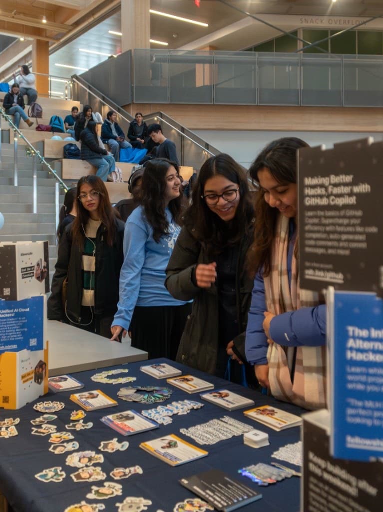 Attendees browsing sponsor table stickers and MLH materials near the Snack Overflow sign.